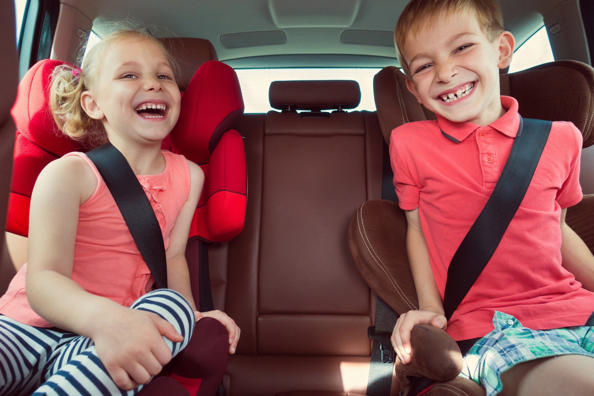 children laugh in the rear seat of a vehicle