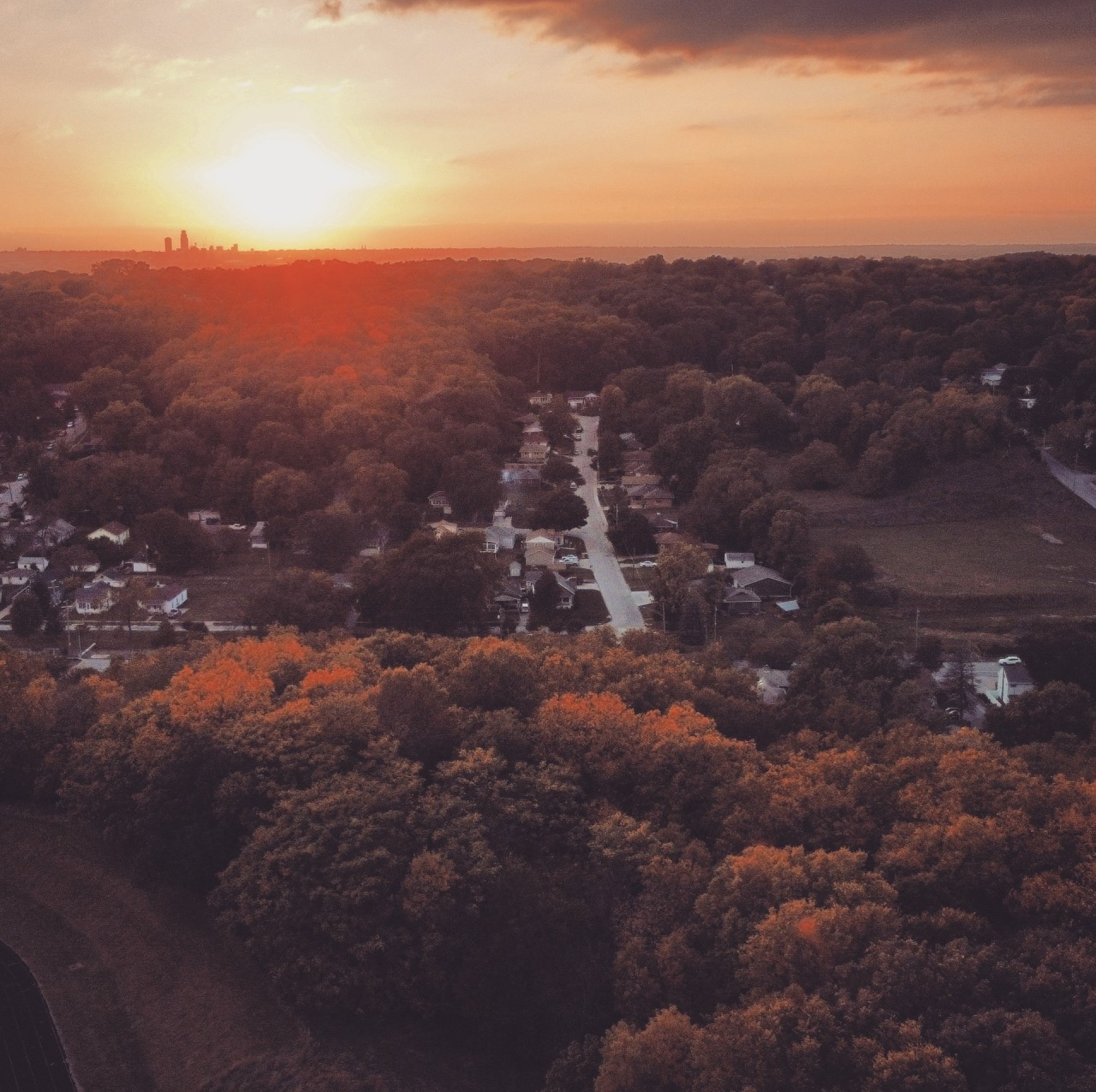 sun casts over fall foliage while showing they Omaha skyline