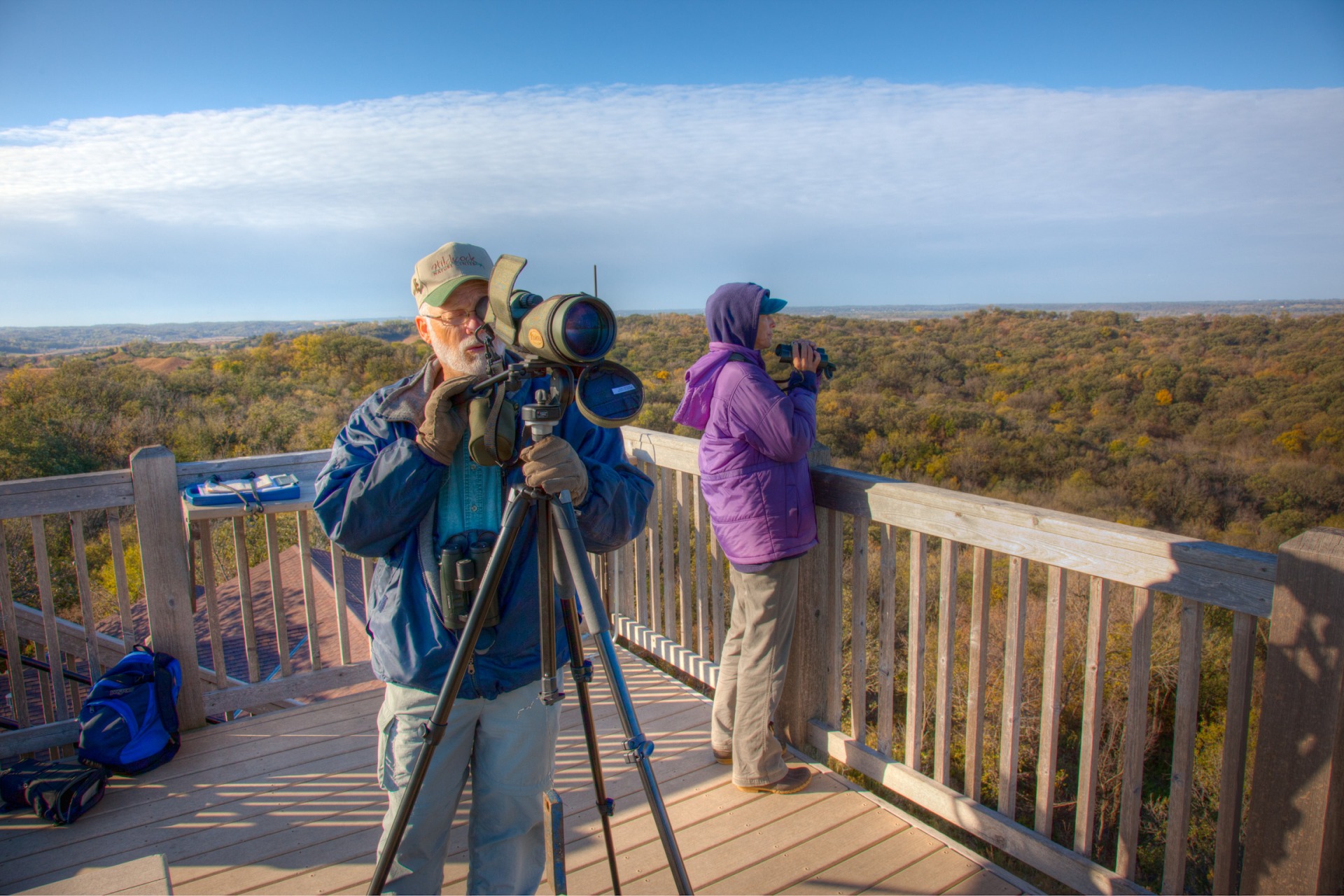 Visitors use binoculars and photo lenses to capture images from an observation deck