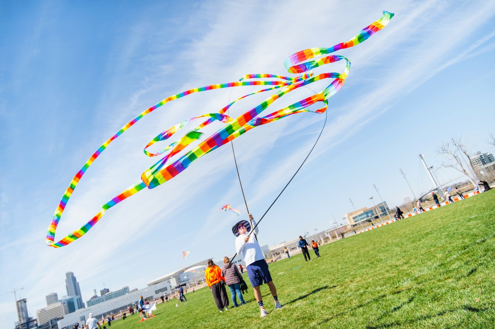 A large vibrant kite is waived by a person wearing patriotic socks and hat 