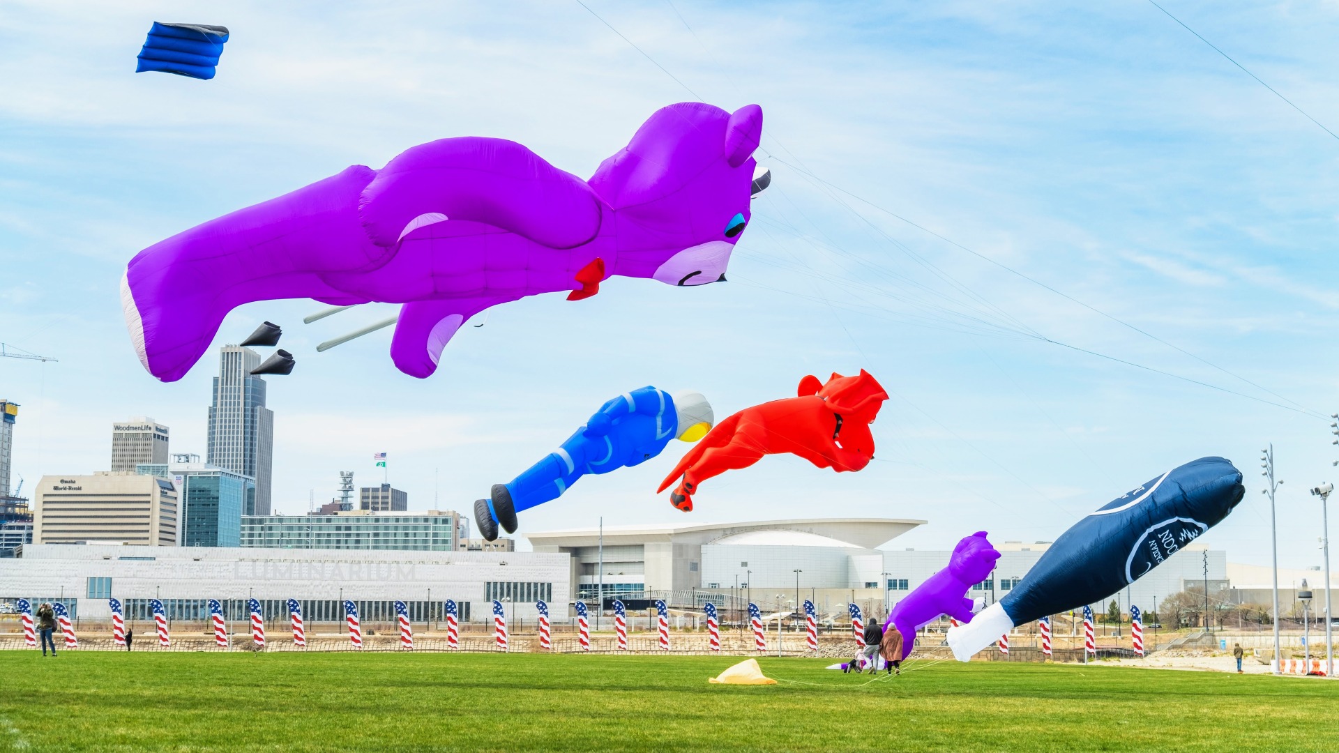 Large inflatable kites hit the air with the Omaha skyline in the distance