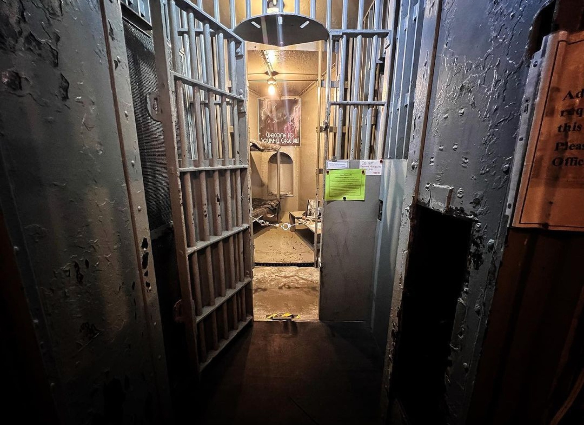 a historic jail door opens to an old jail cell